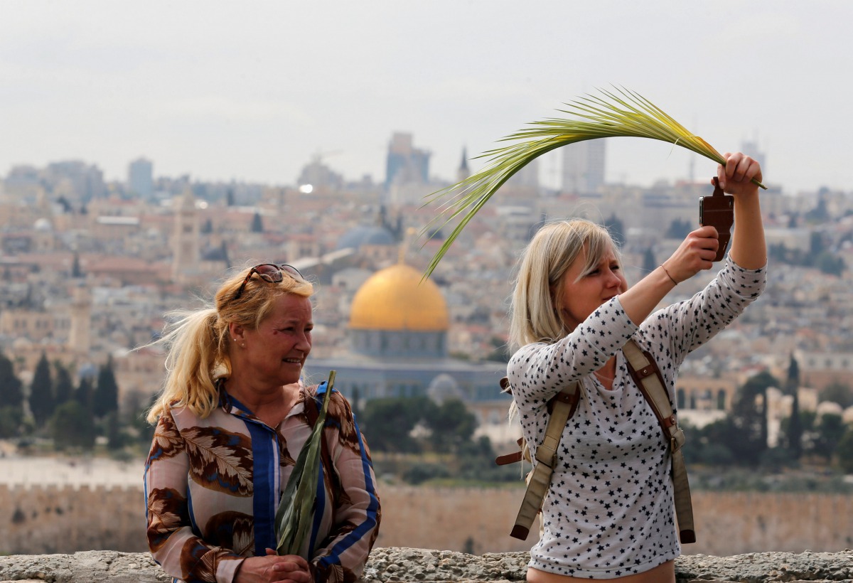 Christian worshippers hold palm fronds and take a photo as they take part in a Palm Sunday procession on the Mount of Olives in Jerusalem April 9, 2017. REUTERS/Amir Cohen