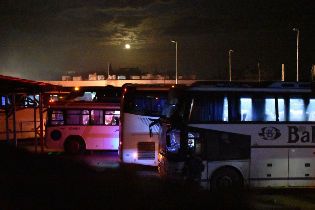 A picture taken on April 14, 2017 shows buses parked in Aleppo, waiting for militants and members of their families from Madaya and Zabadani, to board and to head to Ramousseh as part of the deal between the opposition and the Syrian government. AFP / Geo