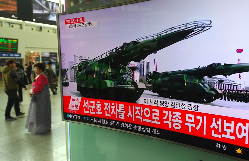 People walk past a television screen broadcasting live footage of a parade to mark the 105th anniversary of the birth of North Korea's founder Kim Il-Sung, at a railway station in Seoul on April 15, 2017.   AFP / JUNG Yeon-Je
