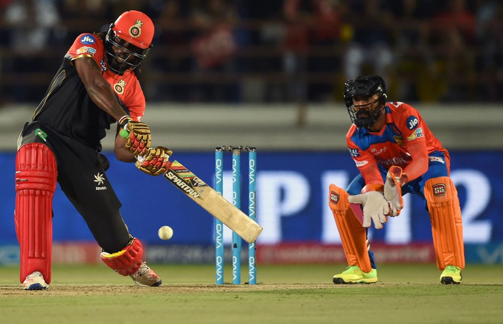 (FILES) This file photo taken on April 18, 2017 shows Royal Challengers Bangalore cricketer Chris Gayle (L) being watched by Gujarat Lions wicketeeper Dinesh Karthik during the 2017 Indian Premier League (IPL) Twenty20 cricket match between Gujarat Lions 