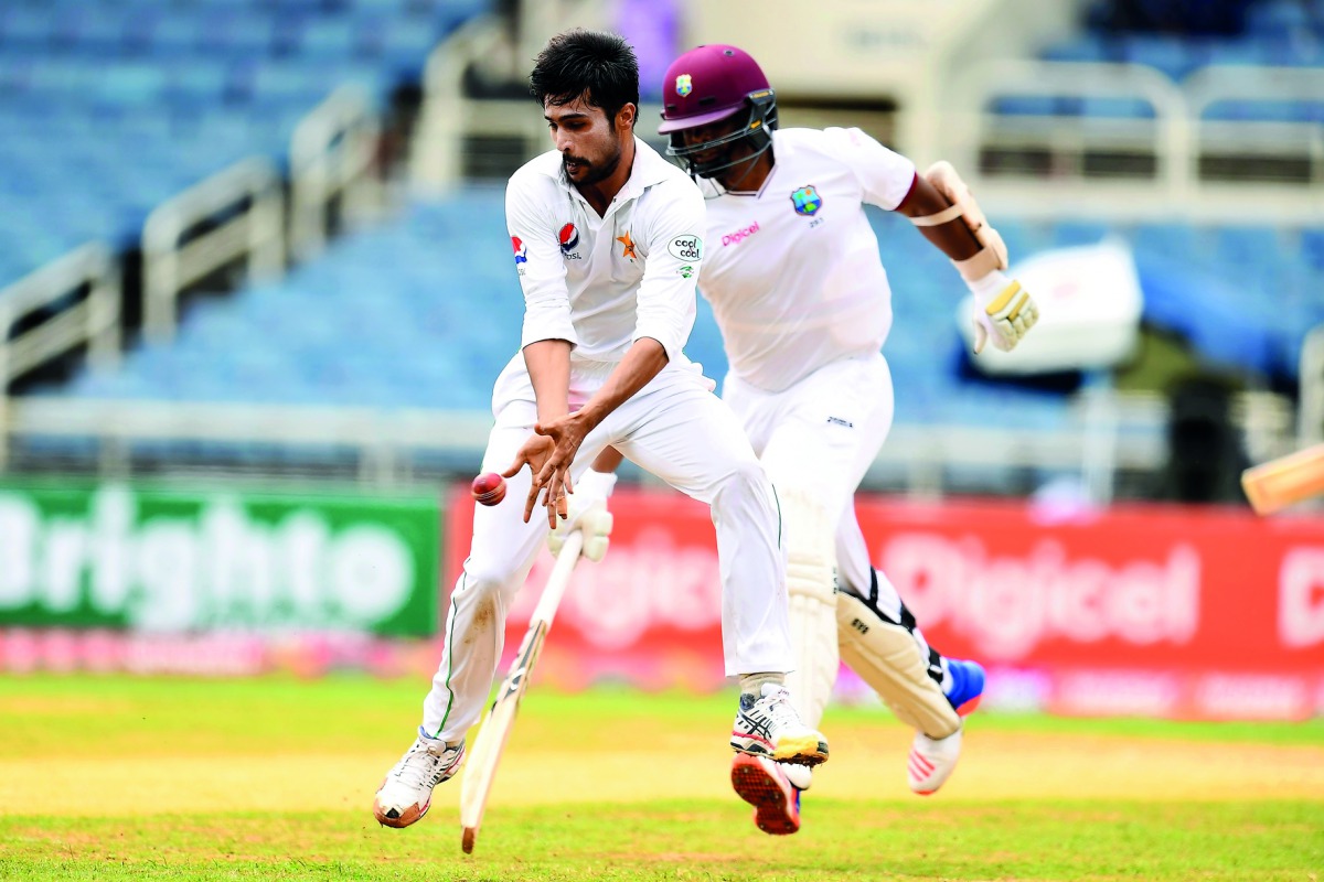 Pakistan's bowler Mohammad Amir (left) stops the ball as West Indies' batsman Shannon Gabriel takes a run on day three of their first Test in Kingston, Jamaica, yesterday. 