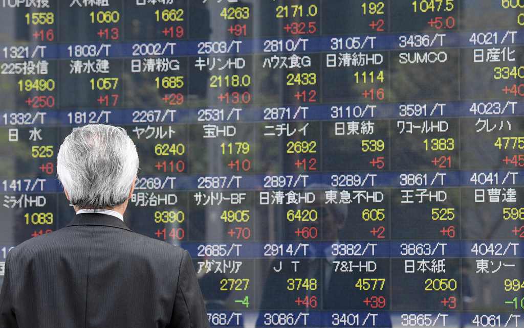 A businessman looks at an electronic share indicator at the window of a securities company in Tokyo on April 24, 2017. AFP / Toshifumi Kitamura
