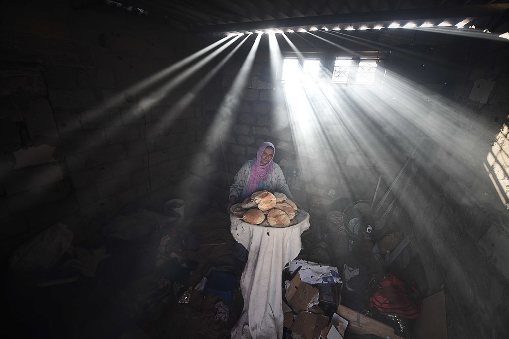 KHAN YUNIS, GAZA - APRIL 19: A Palestinian woman bakes bread by firing pieces of wood and cartons due to power cut and lack of gas in Khan Yunis, Gaza on April 19, 2017. (Abed Zagout - Anadolu Agency)