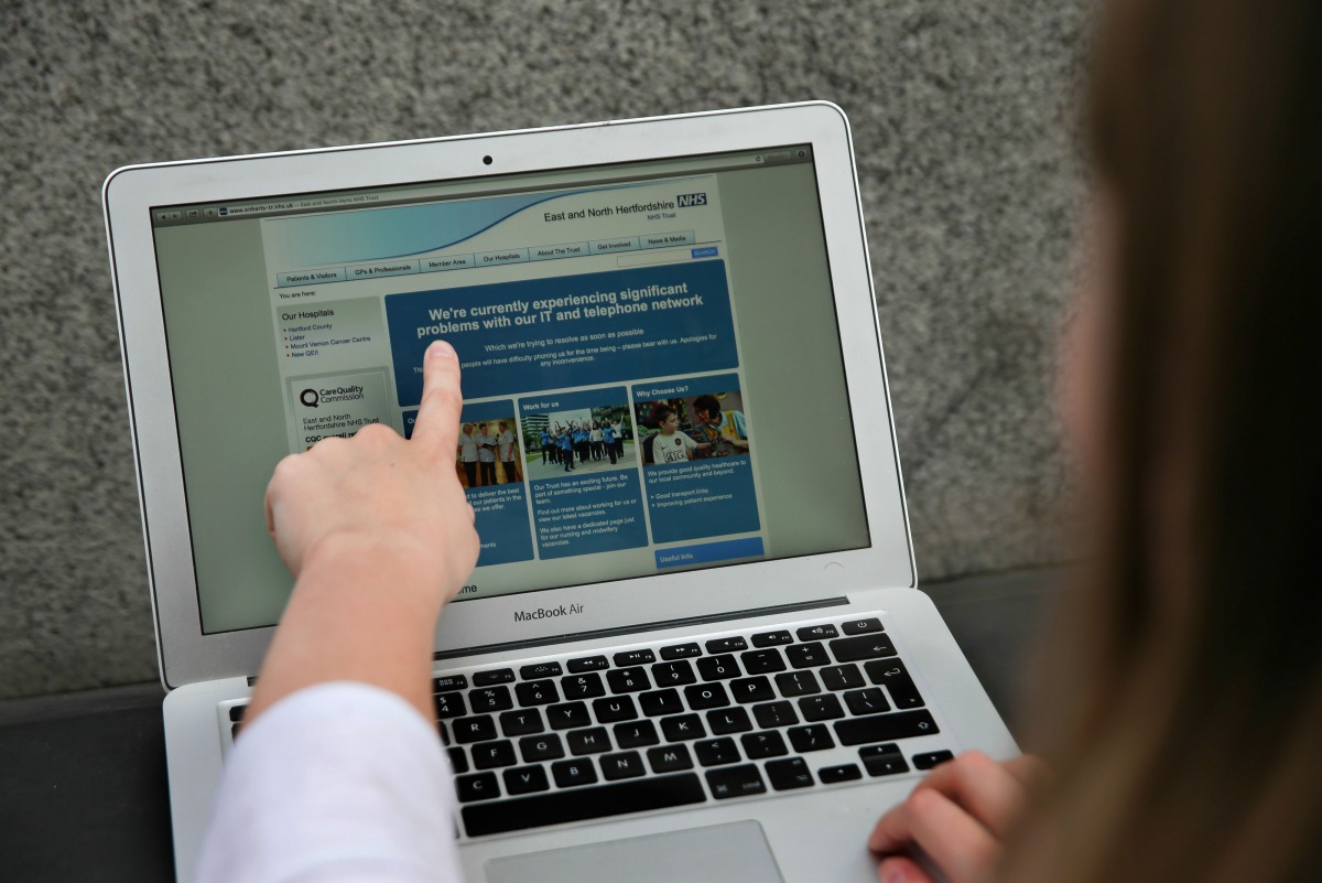 In this posed picture photograph, a woman points to the website of the NHS East and North Hertfordshire notifying users of a problem in its network in London on May 12, 2017 (AFP / Daniel Leal-Olivas) 