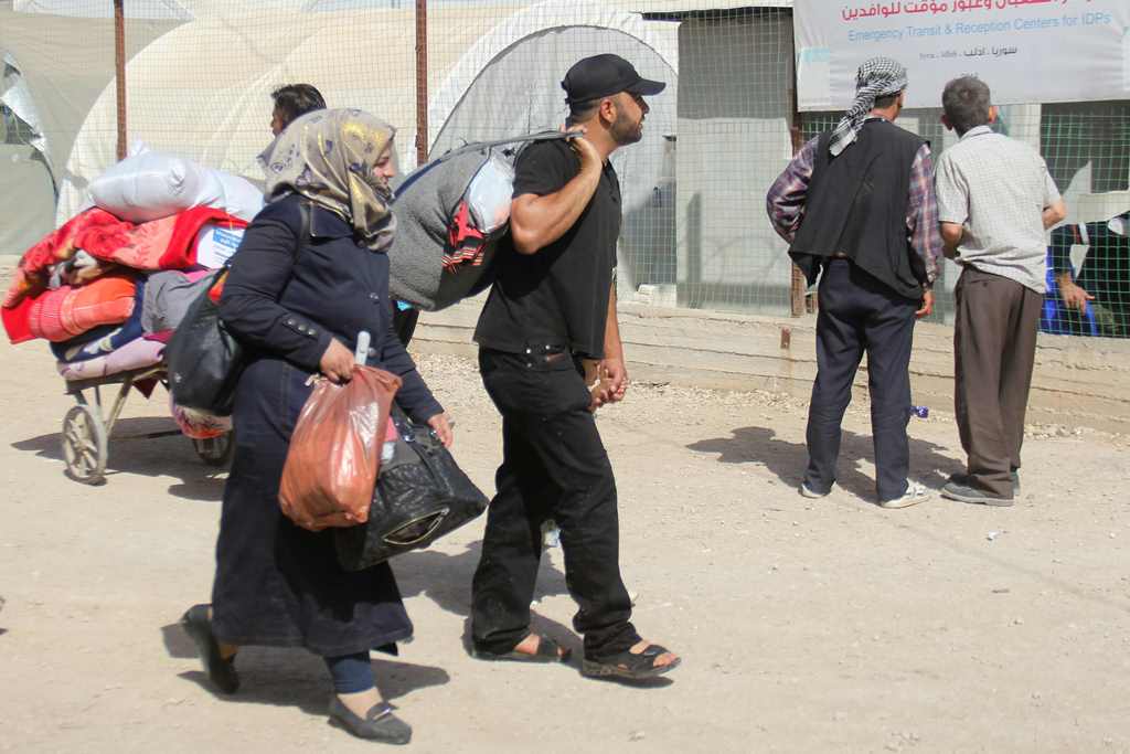 Syrians carry their belongings as civilians and rebels, who were evacuated from the Qabun district in northeast Damascus, arrive at a temporary camp in the northern countryside of Idlib province on May 15, 2017. AFP / Omar Haj Kadour