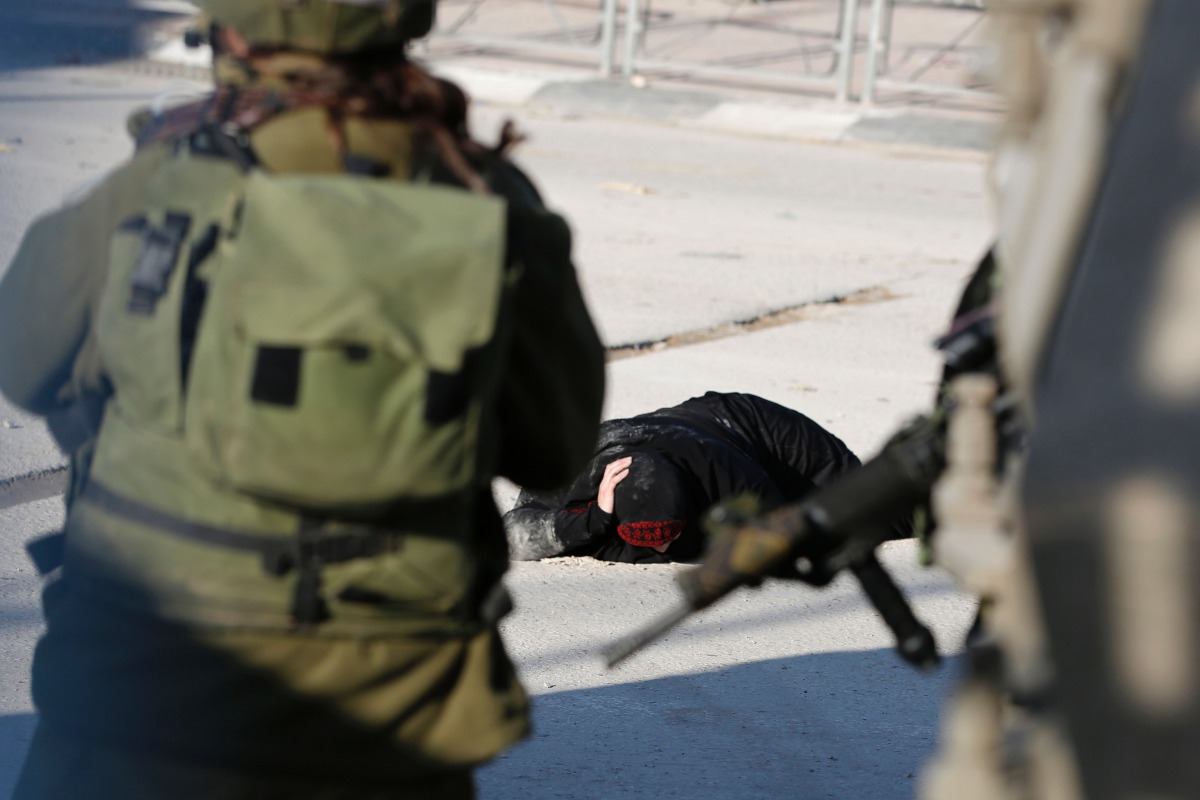 FILE PHOTO: A Palestinian woman lies on the ground after she was shot and wounded by Israeli security forces at Qalandia checkpoint between Jerusalem and the occupied West Bank on December 30, 2016 (AFP / Abbas Momani) 
