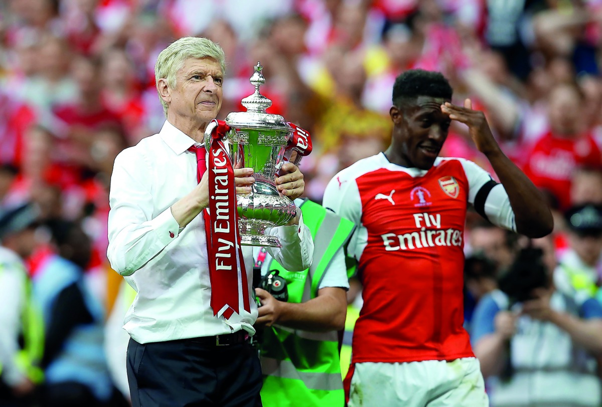 Arsenal manager Arsene Wenger and Danny Welbeck celebrate with the FA Cup trophy after defeating Chelsea in the final at Wembley Stadium in London yesterday.
