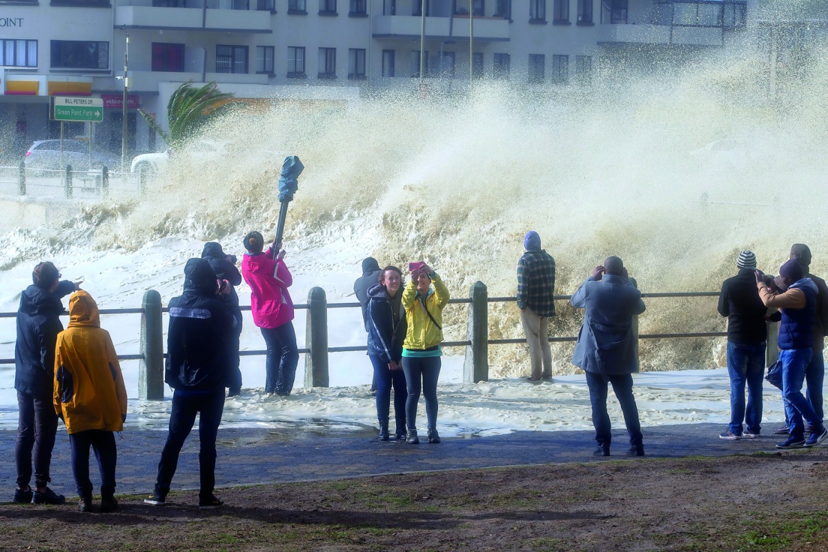 People stand over the bridge as the huge waves hit coastline during the heavy storm in Cape Town, yesterday.