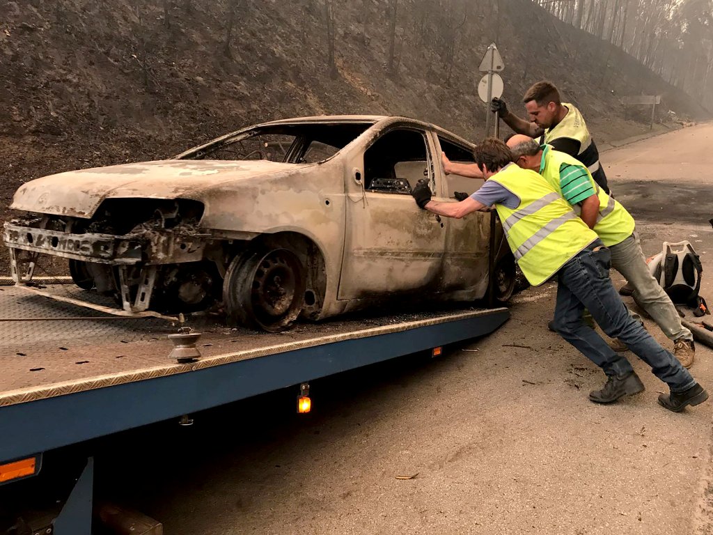 A burned car is moved onto a towing truck during a forest fire near Pedrogao Grande, Portugal June 18, 2017. REUTERS/Guillermo Martinez
