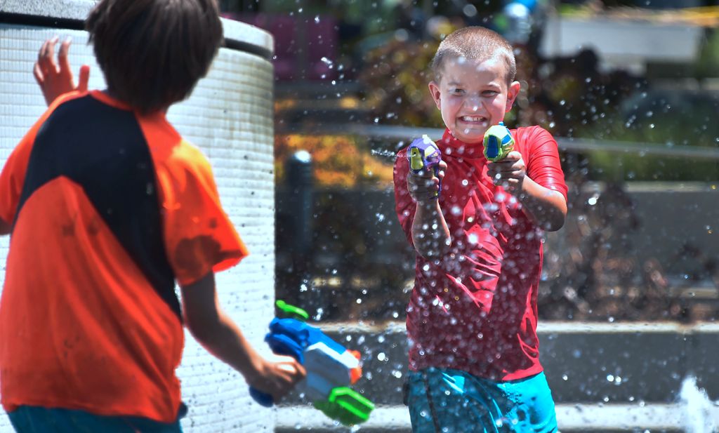 Boys cool of with water guns at the Grand Park splash pad in downtown Los Angeles, California on June 19, 2017, amid a Southern California heatwave with highs again forecast to hit triple-digits in some Los Anegels County communities. / AFP / FREDERIC J. 