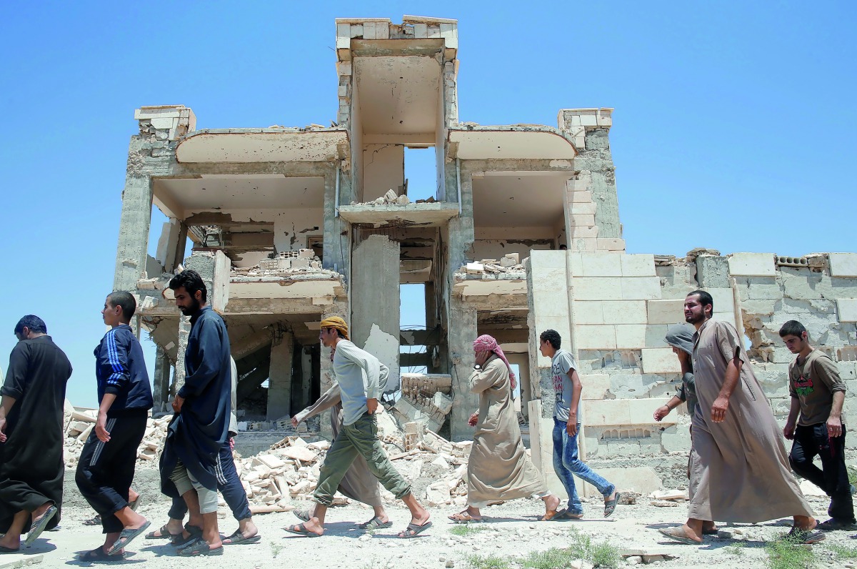Islamic State prisoners, who were pardoned by a council that is expected to govern Raqqa once the group is dislodged, walk in Ain Issa village, north of Raqqa, yesterday.