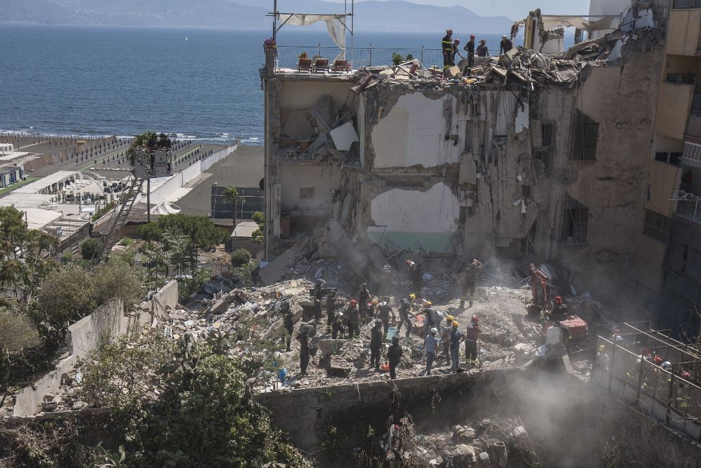 Firefighters throw away the debris of a collapsed building on the binaries of the railway after two floors collapsed in a small four-storey building in Torre Annunziata, a town near the Italian city of Naples, on July 7, 2017. / AFP / Renato Esposito.