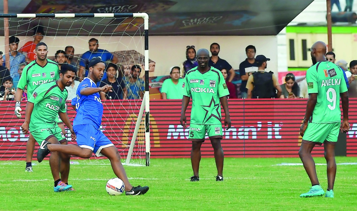 Former FC Barcelona player, Brazilian Ronaldinho (third left) kicks the ball watched by Pakistani football players during a friendly match in Lahore yesterday. 