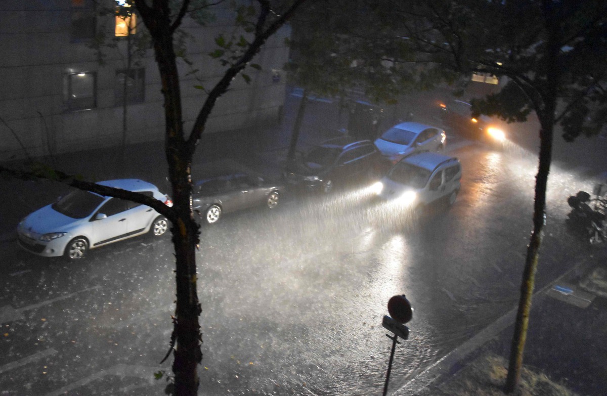 A person drives a vehicle under a heavy rainfall on July 9, 2017 in the 20th district of Paris. Paris subway authorities closed metro stations due to flooding after thunderstorms and heavy rain pounded the French capital, officials said on July 10, 2017. 