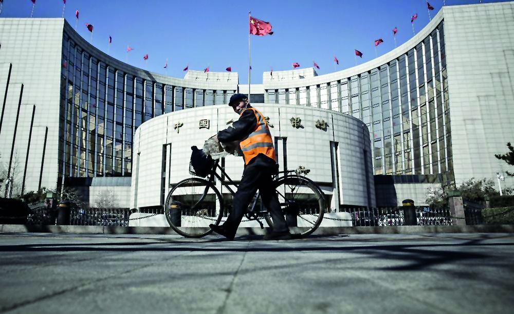 A man pushes a bicycle past the People's Bank of China headquarters in Beijing.