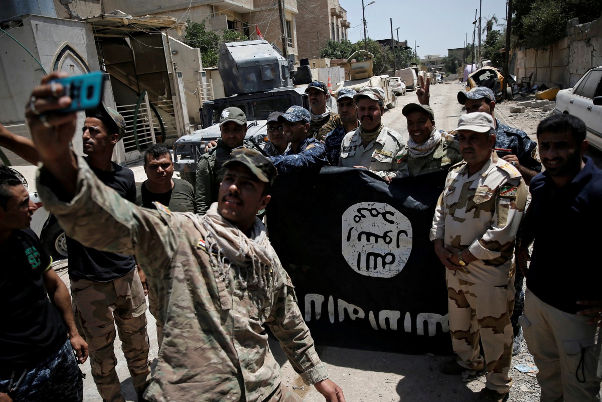 Members of the Iraqi Army's 9th Armoured Division are photographed with an Islamic State flag, claimed after fighting with Islamic State militants in western Mosul, Iraq June 17, 2017. (REUTERS/Alkis Konstantinidis/File Photo)