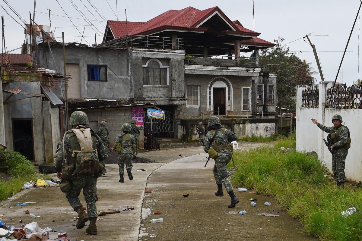 This photo taken on July 22, 2017 shows Philippine Marines taking cover from sniper fire while on patrol at the frontline in Marawi on the southern island of Mindanao, as fighting between government troops and Islamist militants enters its second month. A