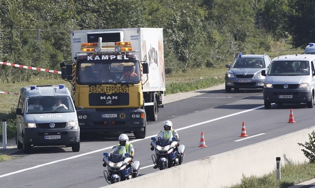 A refrigerated truck involved in similar incident is towed and escorted by police along a highway near Neusiedl am See, Austria, on 27 August 2015 (AFP)