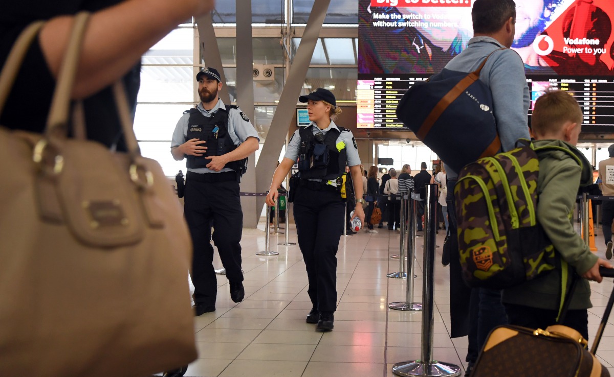 Police walk past passengers as they patrol Sydney Airport on July 30, 2017. (AFP / WILLIAM WEST)