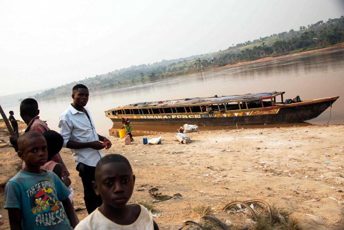 This file photo taken on July 28, 2017 shows people standing next to an empty boat as the traffic on the Kasai river has been slowed down due to insecurity at the port of Tshikapa, Democratic Republic of Congo. AFP / Junior D. Kannah