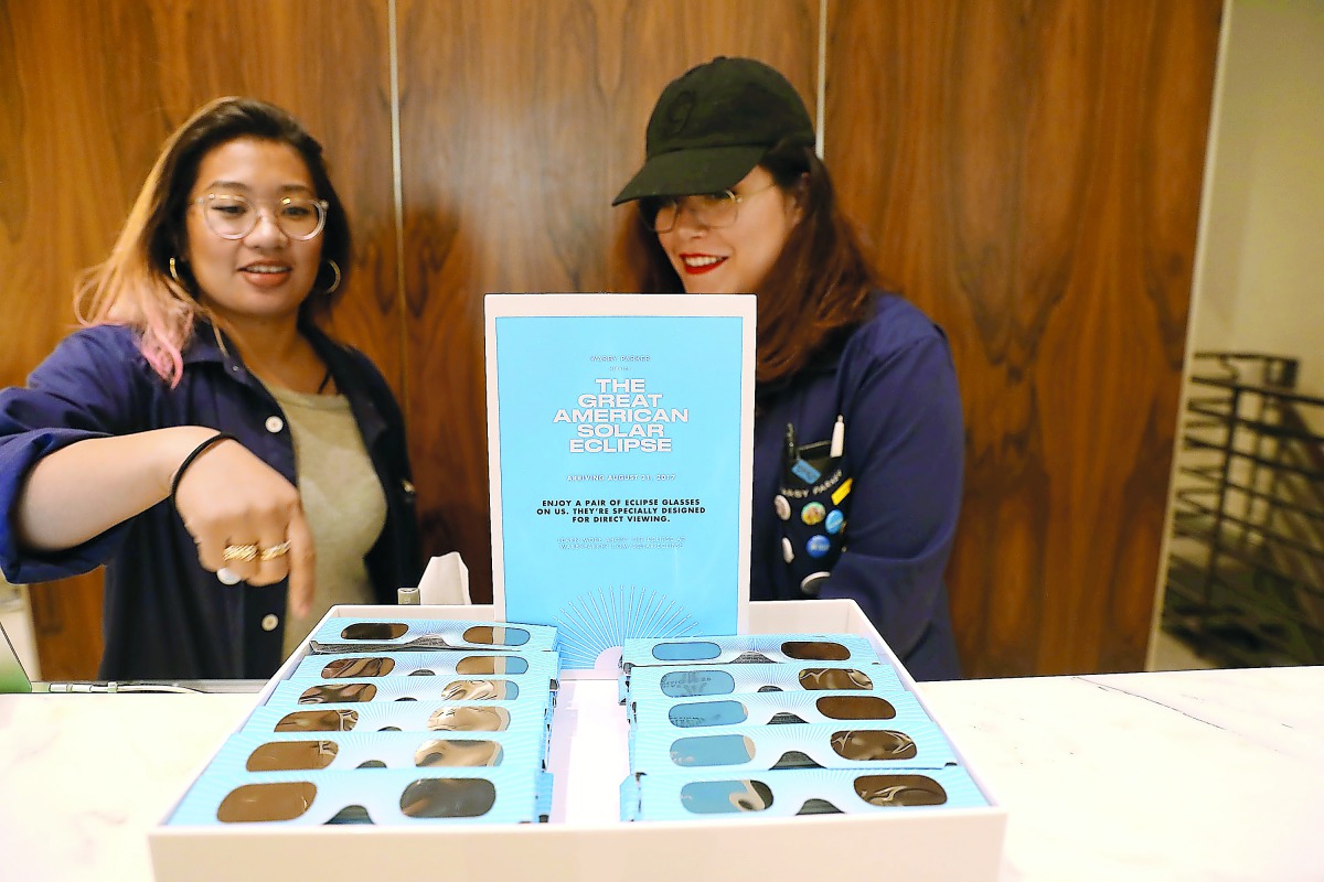 Warby Parker employees unfold pairs of solar eclipse glasses in New York City. To view the upcoming total solar eclipse on August 21 eye protection is essential. The designer eyeglass store expects to give out thousands of the glasses before the event