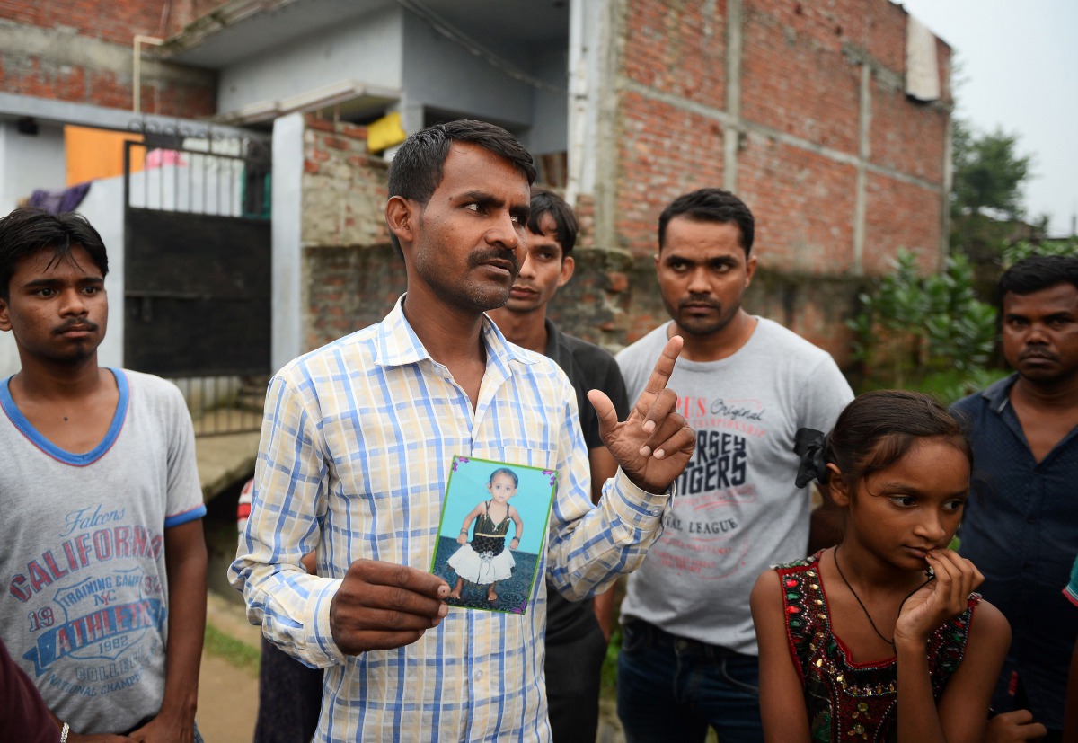 Mohammad Zahid, who lost his five-and-a-half year old daughter Khushi, holds his daughter's photograph in Gorakhpur in the Indian state of Uttar Pradesh, on August 14, 2017. AFP / Sanjay Kanojia