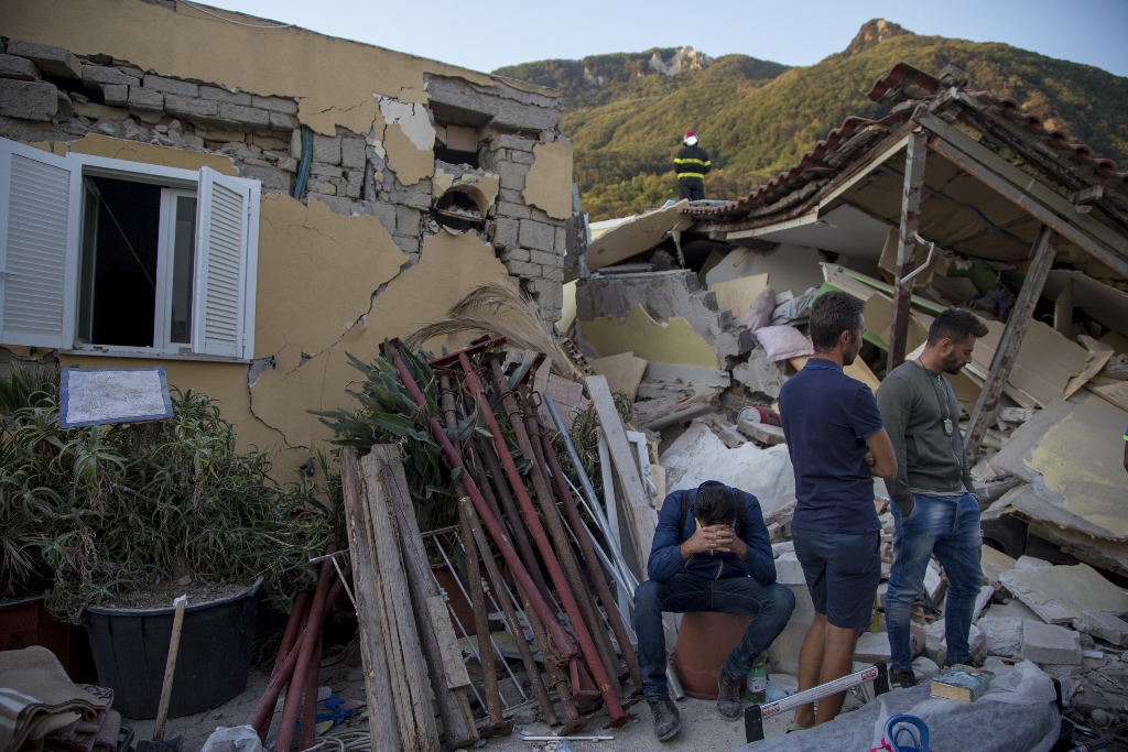 A man sits on a bucket as others look on near a wracked building after 4.0-magnitude richter scale earthquake hit Ischia Island's Casamicciola Terme of Naples, Italy on August 22, 2017. ( Alessio Paduano - Anadolu Agency ).
