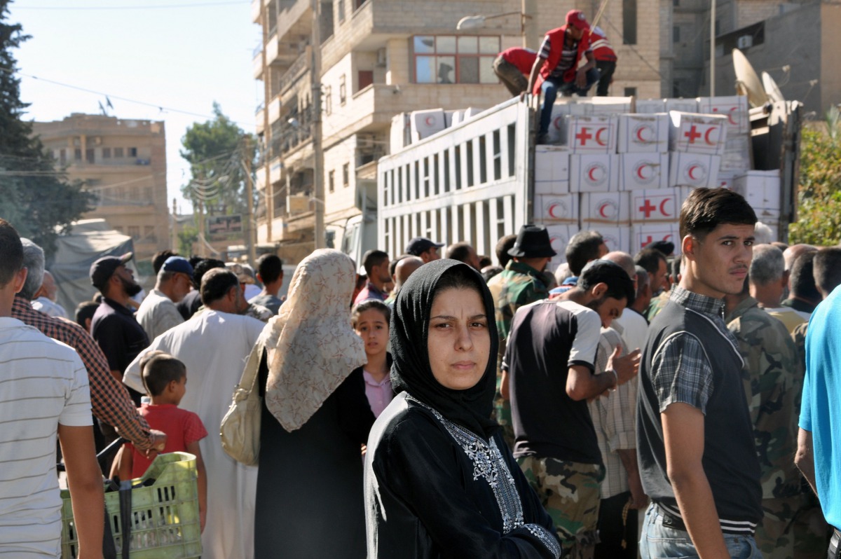 Local residents gather to receive humanitarian aid parcels provided by the Syrian Red Crescent in the northeastern city of Deir Ezzor on September 9, 2017. / AFP / STRINGER
