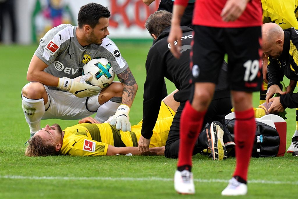 Dortmund's Swiss goalkeeper Roman Buerki kneels next to injured teammate defender Marcel Schmelzer during the German first division Bundesliga football match SC Freiburg vs Borussia Dortmund in Freiburg, southwestern Germany, on September 9, 2017.  AFP / 