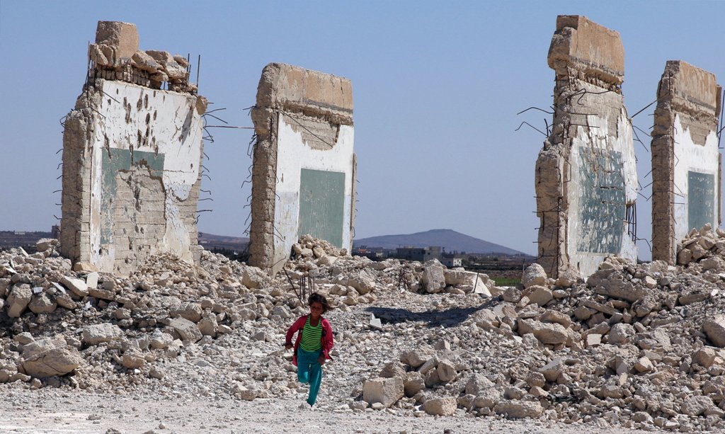 A girl runs near a damaged site in the Quneitra countryside, Syria September 12, 2017. REUTERS/Alaa Al-Faqir