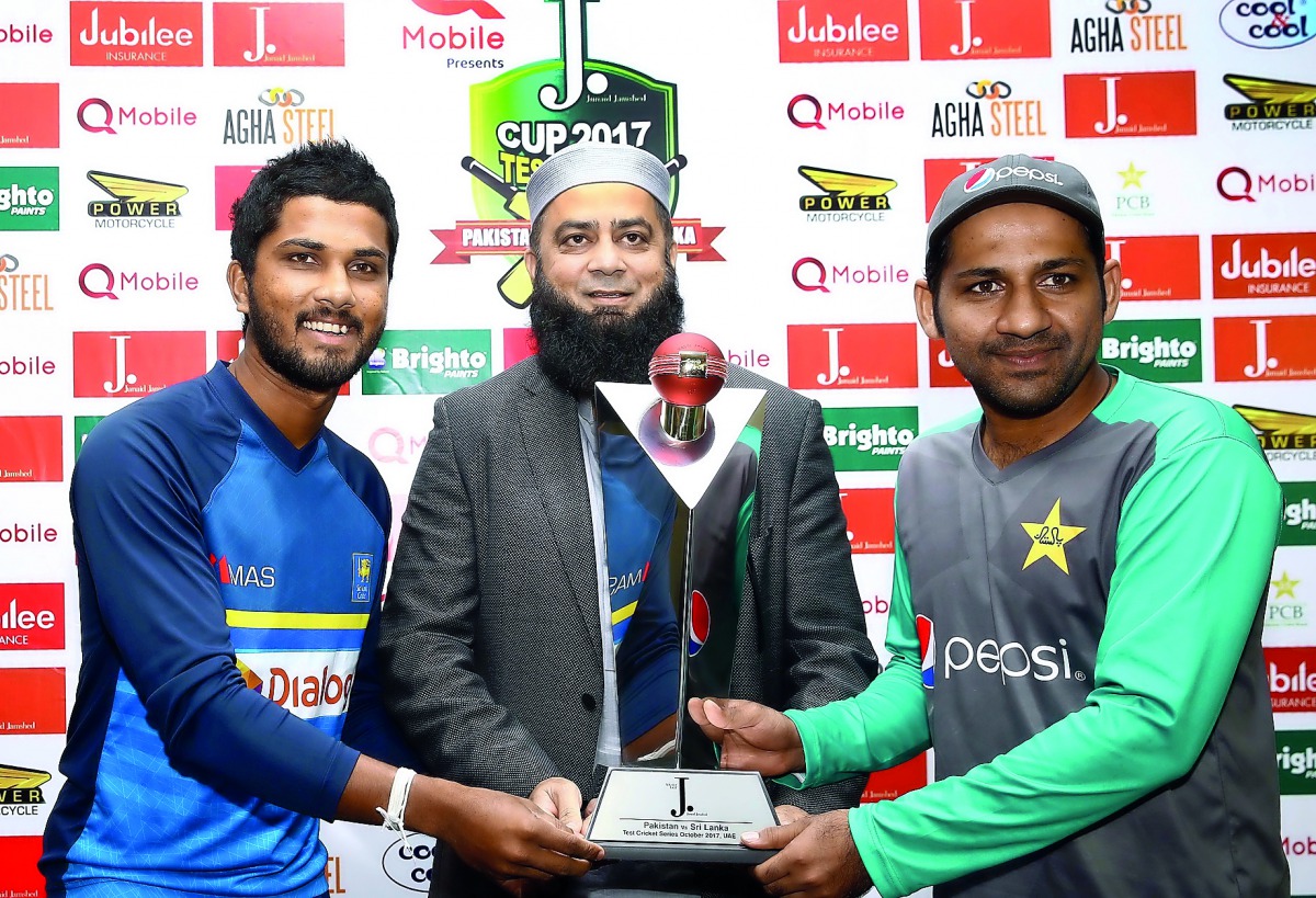 Rival captains Sarfraz Ahmed (right) of Pakistan and Dinesh Chandimal (left) of Sri lanka pose with the trophy ahead of Test series in Abu Dhabi yesterday.