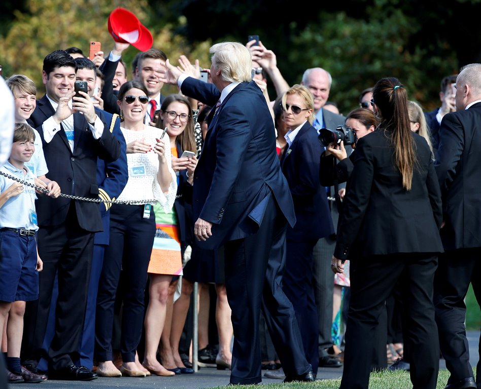 US President Donald Trump tosses a hat to supporters as he departs for Bedminster, New Jersey, from the White House in Washington, U.S., September 29, 2017. Reuters/Joshua Roberts 
