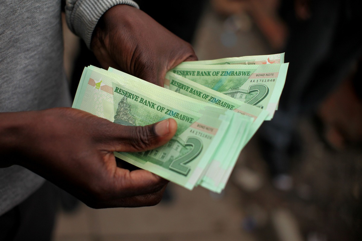 This file photo taken on November 28, 2016 shows a man holding bond notes released by the Reserve Bank Of Zimbabwe in Harare central business centre.  AFP / Wilfred Kajese