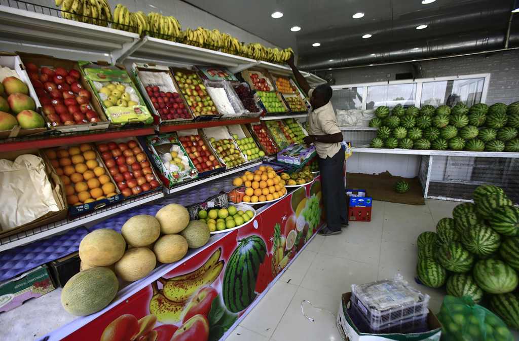 A picture taken on October 2, 2017 shows a fruit seller laying out bananas and organising produce at a shop in the Sudanese capital's twin city of Omdurman.   AFP / ASHRAF SHAZLY
