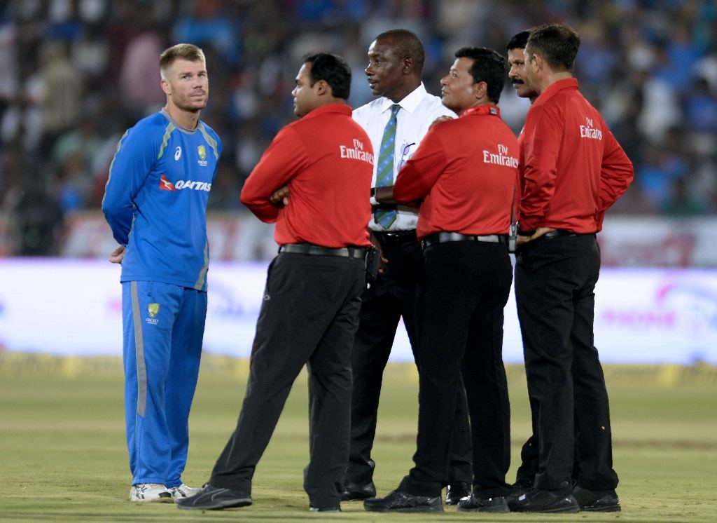 Australia's captain David Warner (L) speaks with match referee Richie Richardson and all the umpires as play is delayed due to wet outfield on the third and final T20 cricket match in a series between India-Australia at the Rajiv Gandhi International Cric