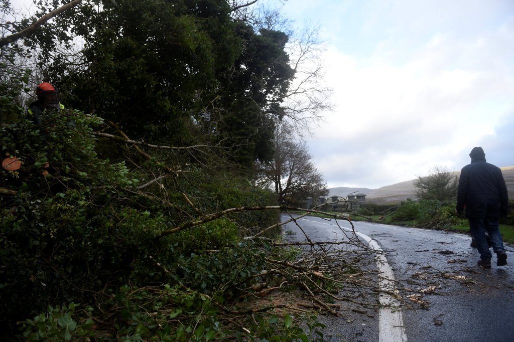 A man walks past a worker clearing fallen trees off a road during Storm Ophelia in the County Clare area of the Burren, Ireland October 16, 2017. REUTERS/Clodagh Kilcoyne