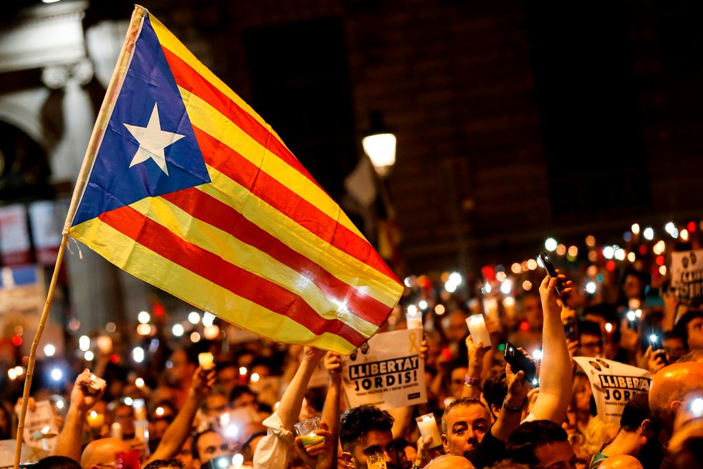 People hold candles and a Catalan pro-independence 'Estelada' flag during a demonstration in Barcelona against the arrest of two Catalan separatist leaders on October 17, 2017. AFP / PAU BARRENA