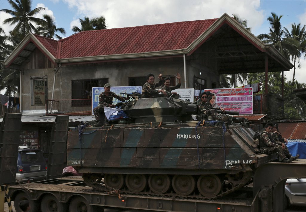 Government soldiers wave while atop of the tank after the send-off ceremony ending their combat duty against pro-Islamic State militant groups, after President Rodrigo Duterte announced the liberation of Marawi city on Monday, in Saguiaran, Lanao Del Sur,