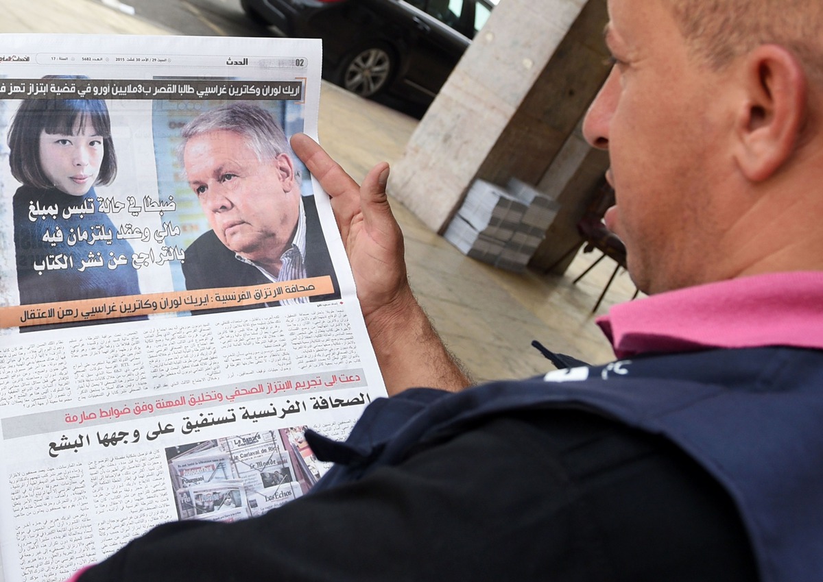 This file photo taken on August 29, 2015 shows a Moroccan man reading the latest issue of Al-Massae daily newspaper in Arabic with on its page portraits of the two French investigative journalists who have been charged in Paris with trying to blackmail th