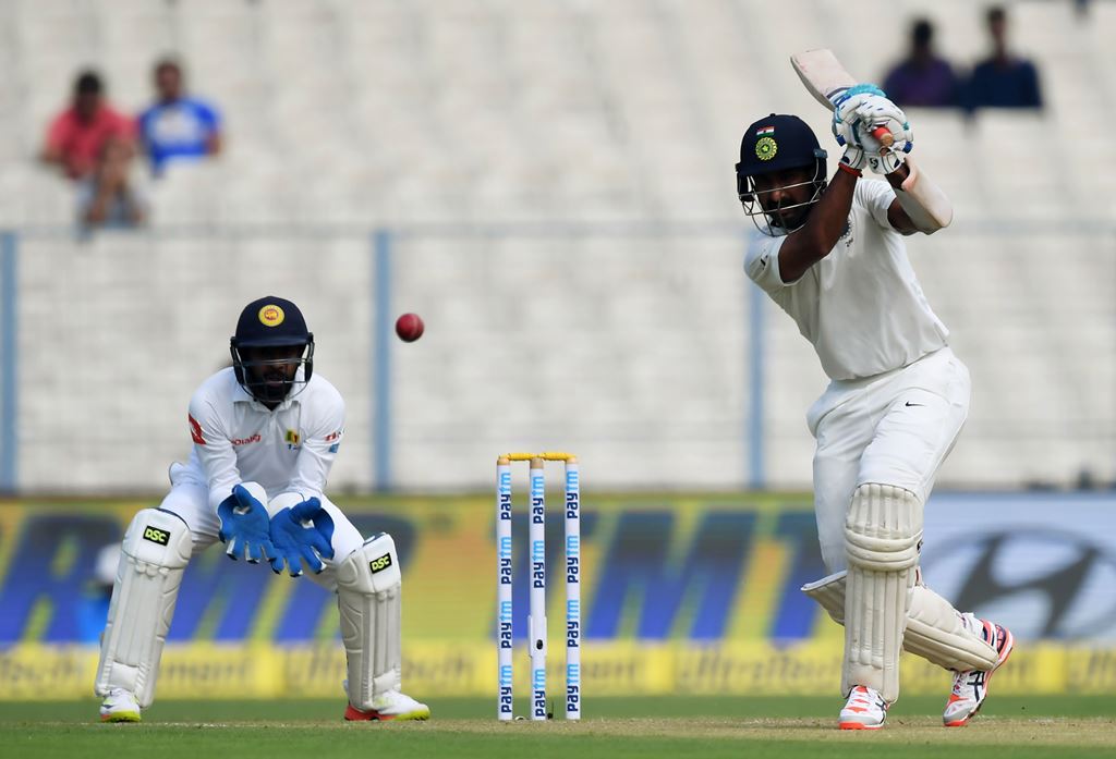 India's Cheteshwar Pujara (R) plays a shot as Sri Lanka's wicket-keeper Niroshan Dickwella looks on during the third day of the first Test between India and Sri Lanka at the Eden Gardens cricket stadium in Kolkata on November 18, 2017. GETTYOUT / AFP / Di