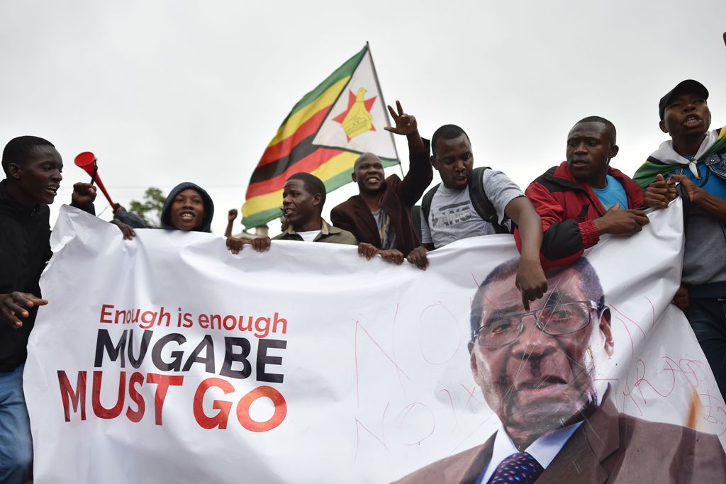 People wave a Zimbabwean national flag and carry banners during a demonstration demanding the resignation of Zimbabwe's president on November 18, 2017 in Harare.  AFP 
