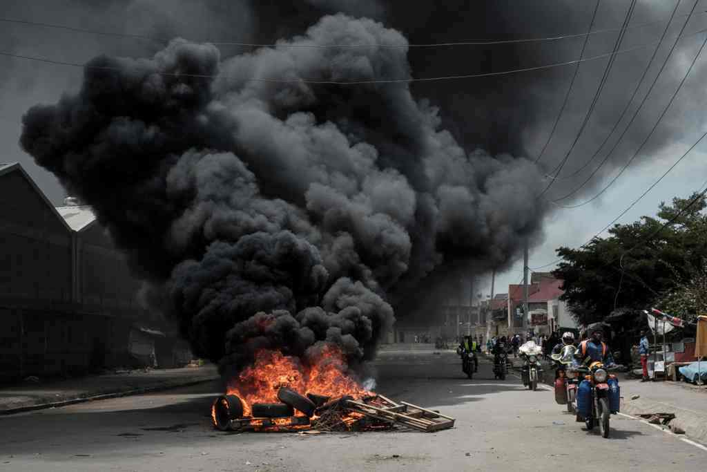 Motorcyclists pass a burning tyre barricade following a demonstration by Kenyan opposition party National Super Alliance (NASA) supporters on November 17, 2017 in Nairobi.