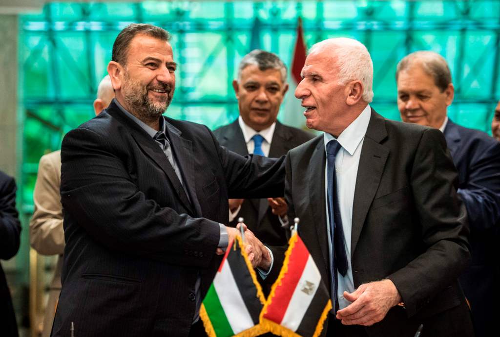 A file photo of Fatah's Azzam al-Ahmad (R) and Saleh al-Aruri (L) of Hamas shaking hands after signing a reconciliation deal in Cairo October 12, 2017. / AFP / KHALED DESOUKI