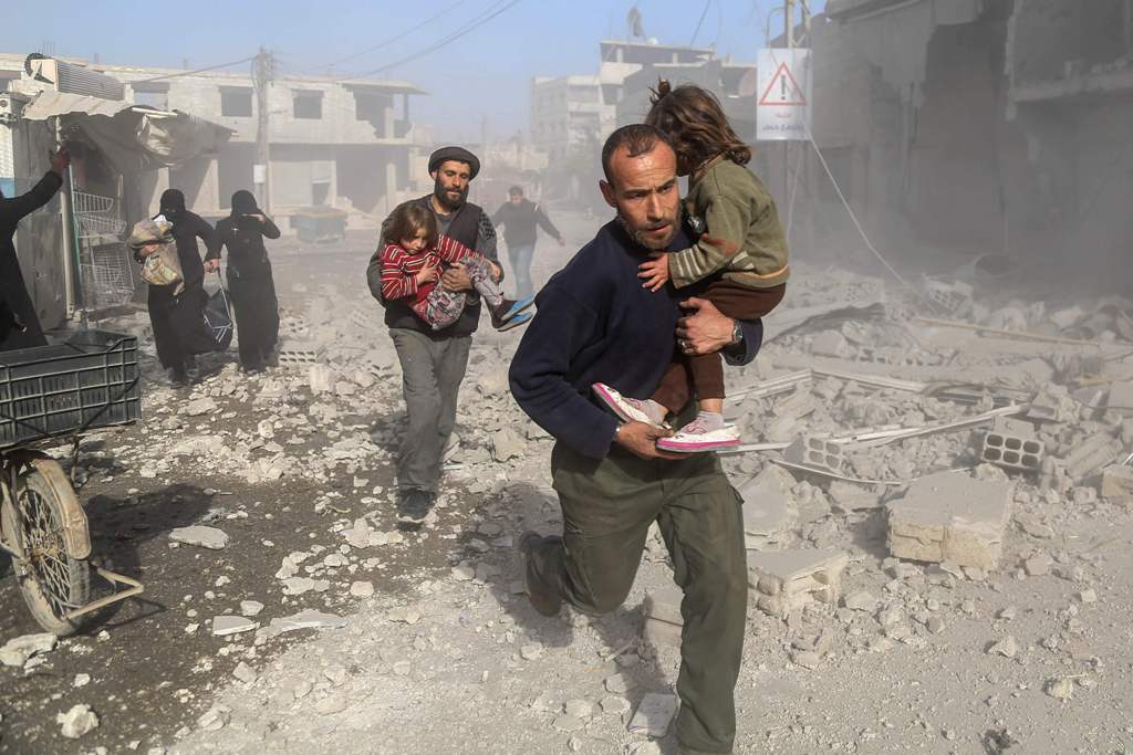Syrians make their way through debris following a reported air strike in the rebel-held town of Beit Sawa, in the eastern Ghouta region on the outskirts of the capital Damascus, on December 3, 2017. / AFP / Amer ALMOHIBANY
