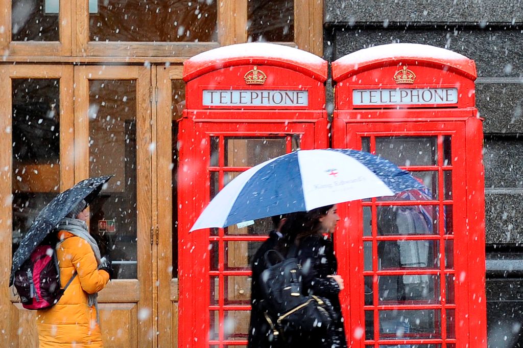 Pedestrians walk as snow falls over central London on December 10, 2017. AFP / DANIEL SORABJI
