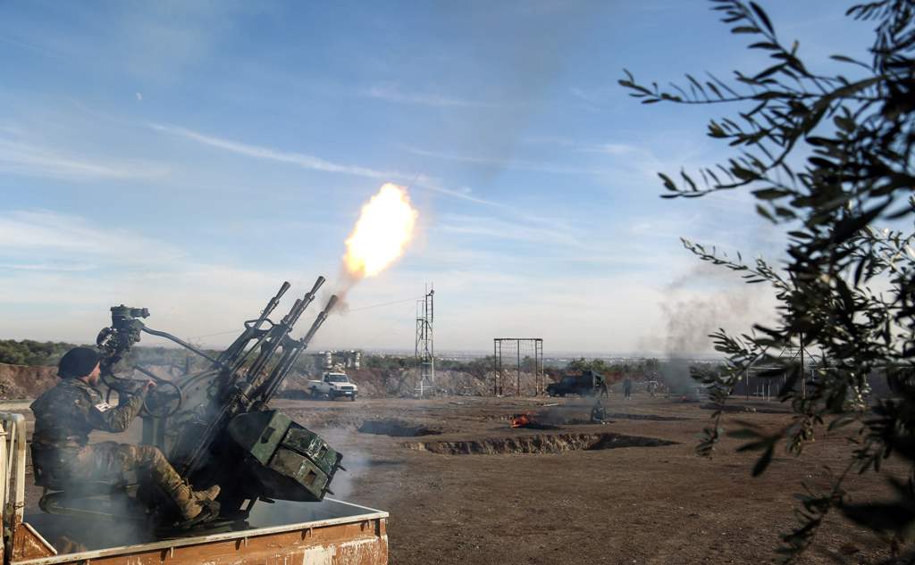 A Syrian rebel fighter belonging to the US-backed Mutasem brigades fires an anti-aircraft gun mounted on the back of a pickup truck as he receives heavy weapons training near the rebel-held village of Shamarin in the north of Aleppo province, on December 