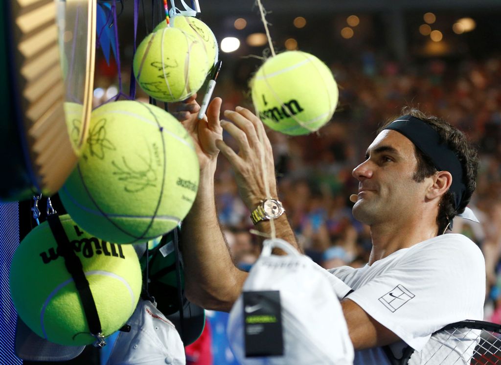 Roger Federer of Switzerland signs autographs during Kids Tennis Day before the Australian Open tennis tournament. REUTERS/Thomas Peter
