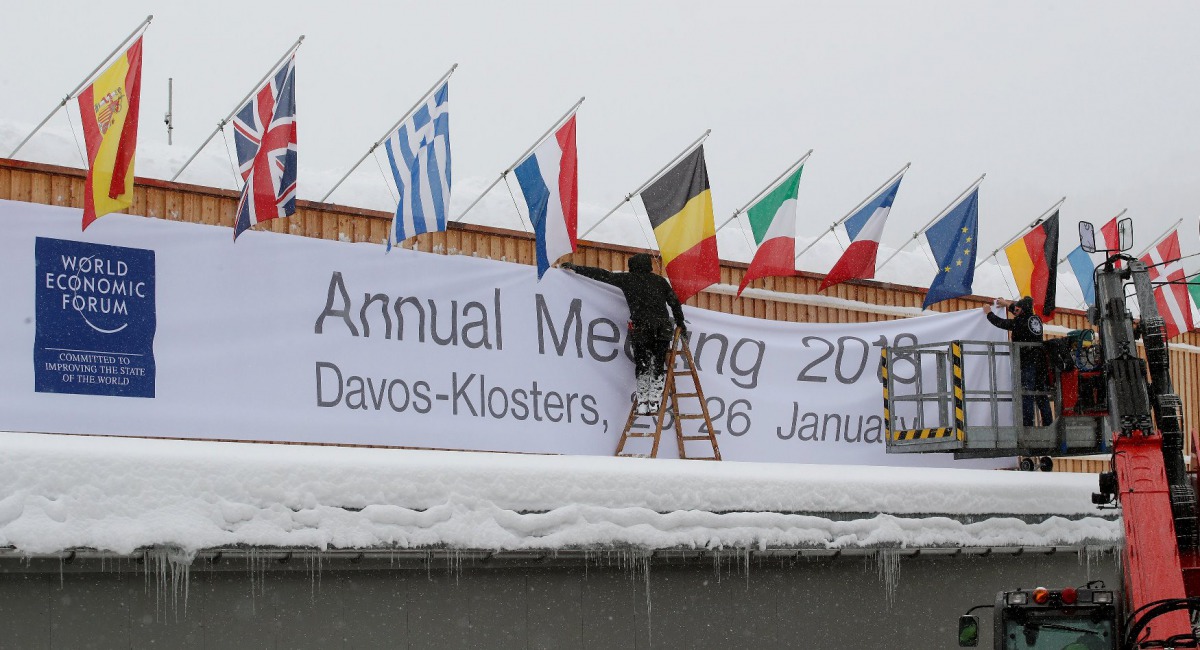 Workers fix a banner on the frontage of the congress centre, the venue of the upcoming World Economic Forum (WEF) in the Swiss mountain resort of Davos, Switzerland, January 18, 2018. REUTERS/Arnd Wiegmann