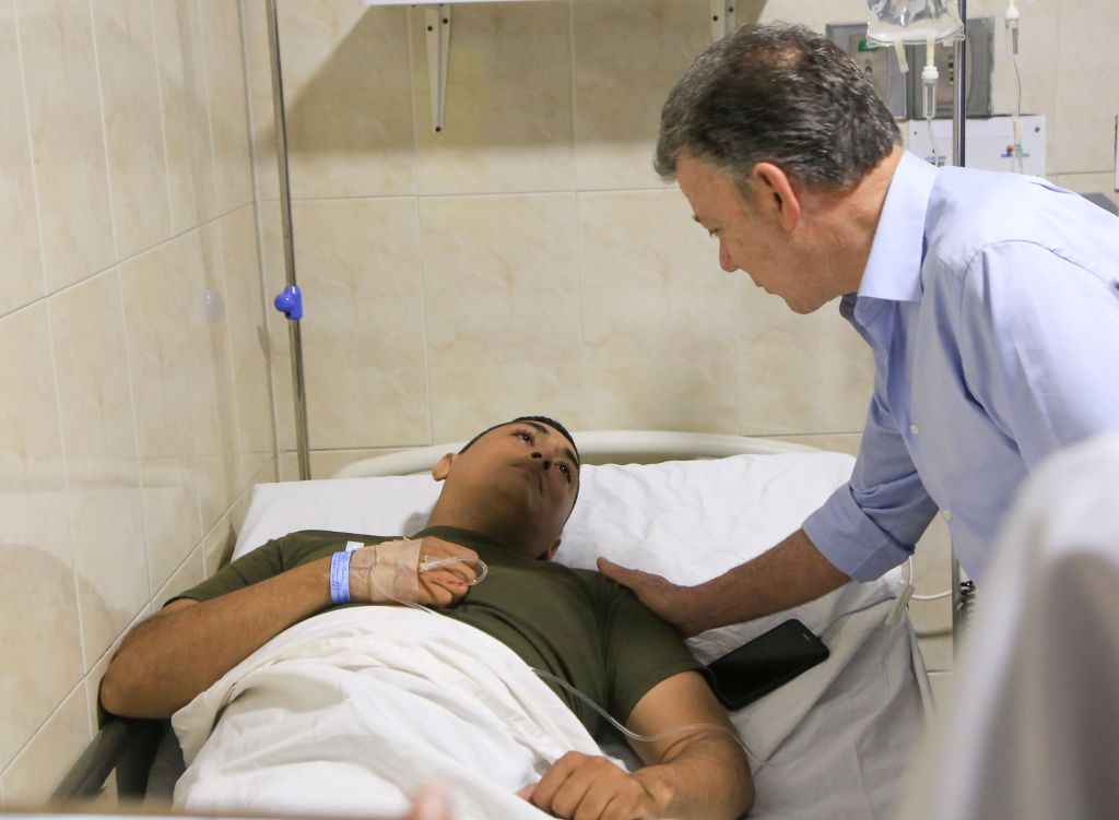 Colombian President Juan Manuel Santos (R) visits an injured police officer at the hospital in Barranquilla, on January 27, 2018. / AFP / JOSE TORRES