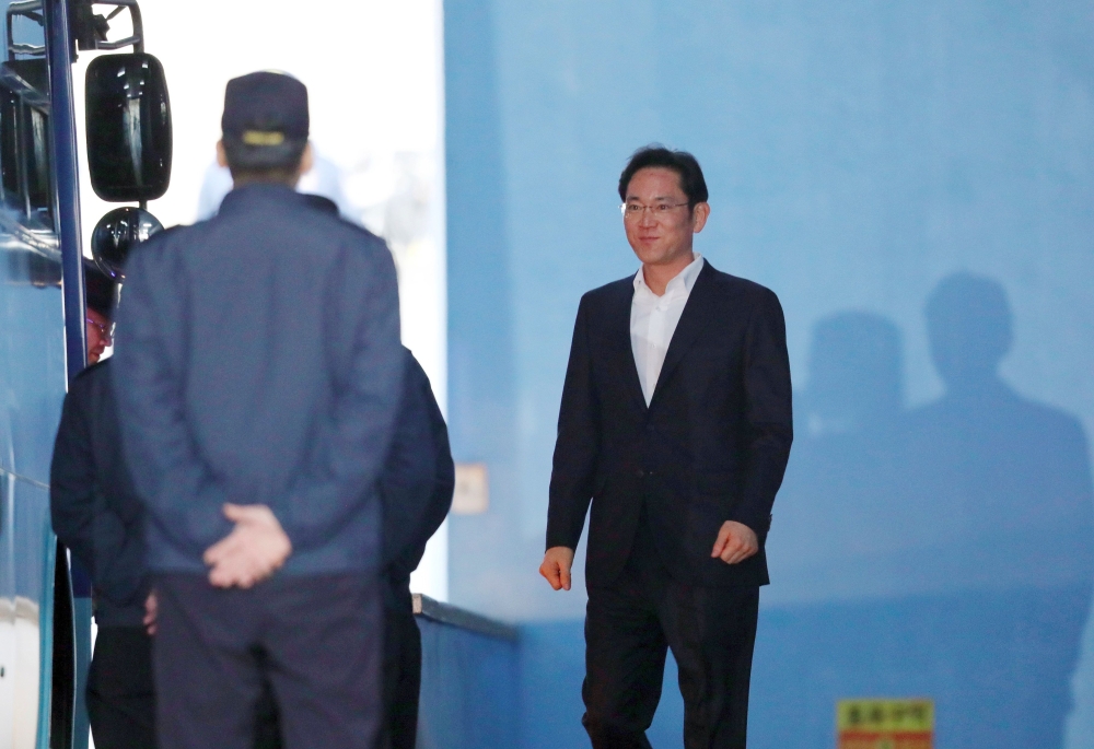 Samsung heir Lee Jae-Yong (R) walks out from a court in Seoul on February 5, 2018, after an appellate court handed him a suspended sentence. / AFP / Dong-A Ilbo /
